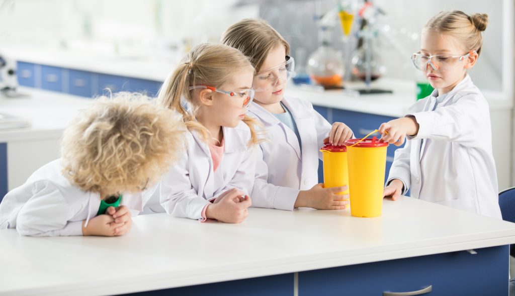 Four kids in science laboratory making experiment